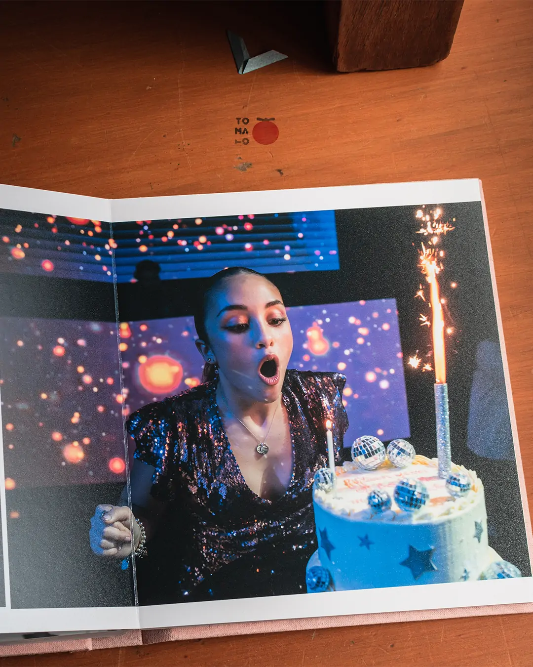 foto del interior de un fotolibro que muestra una quinceañera soplando la vela de la torta